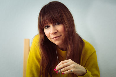 Close-up portrait of redhead woman against wall