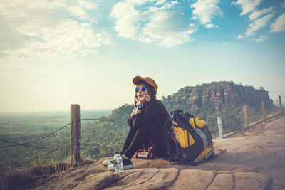 Man sitting on field against sky