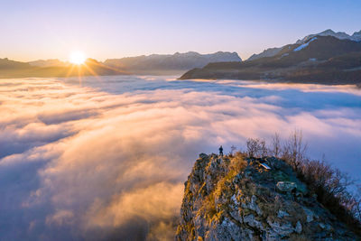 High angle view of man standing on mountain ridge rising above the clouds, hallein, austria