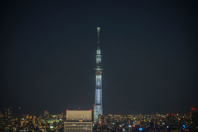 Illuminated buildings in city against clear sky at night