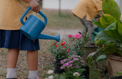 Girl watering potted plants in yard