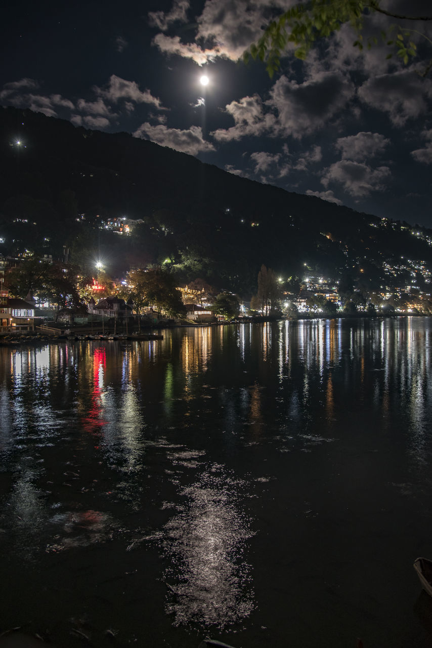 ILLUMINATED CITY BY LAKE AGAINST SKY