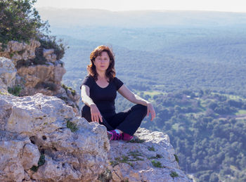 Portrait of young woman relaxing on rocky cliff