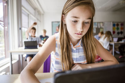 Schoolgirl using digital tablet at desk in classroom