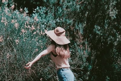 Midsection of woman wearing hat standing by tree