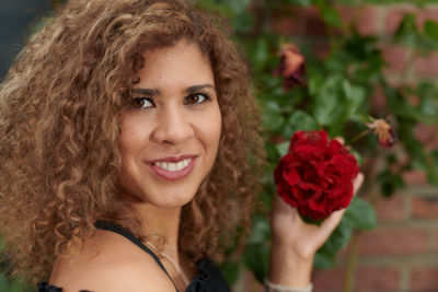 Portrait of smiling woman holding red flower