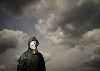 Low angle view of man standing against cloudy sky