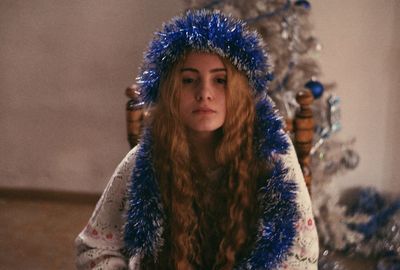 Young woman with blue tinsel while sitting at home