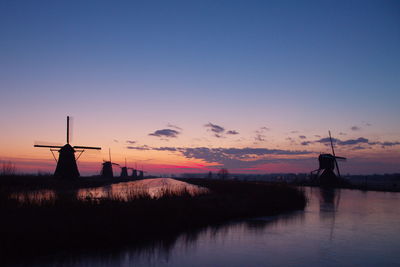 Silhouette of building by sea against sky during sunset