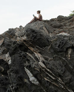 Low angle view of man on rock against sky