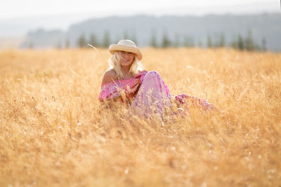 Woman wearing hat sitting on field