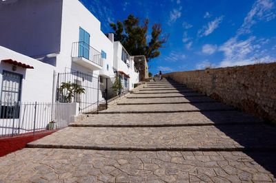 Steps amidst trees against blue sky