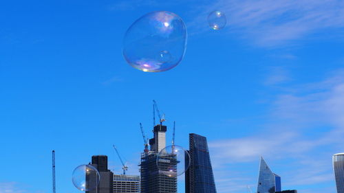 Low angle view of bubbles against buildings in city