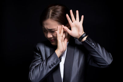 Businessman gesturing against black background