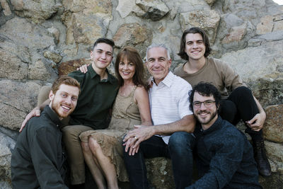 Portrait of happy sons with parents sitting against rock formations at park