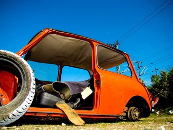 Low angle view of damaged car against blue sky