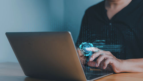 Midsection of woman using laptop at desk in office