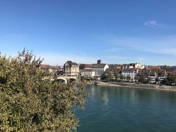 Scenic view of river by buildings against blue sky