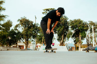 Man skateboarding on road against sky