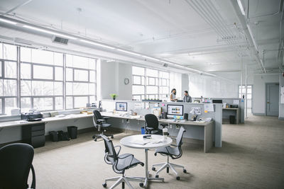 Mid distance view of colleagues discussing paperwork while standing by desk in office