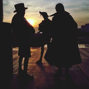 Silhouette people standing against sky during sunset