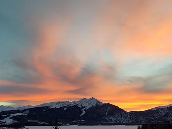 Scenic view of snowcapped mountains against orange sky