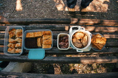 A top view photo of assorted foods on a wooden park bench