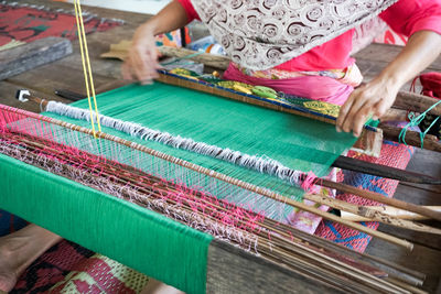 Midsection of woman working on loom