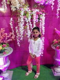 Portrait of girl standing on pink flowering plants
