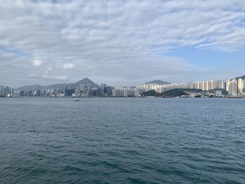 Sea by city buildings against sky