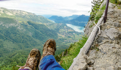 Low section of man on mountain peak against sky