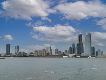 Sea by modern buildings against sky in city