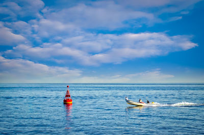 Men riding boat on scenic sea against sky