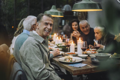 Portrait of happy senior man with friends during dinner party