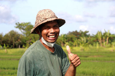 Portrait of man wearing hat standing on field