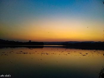Scenic view of lake against clear sky during sunset