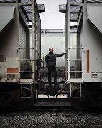 Portrait of mid adult man standing on train coupling