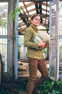 Young woman holding a big ripe pumpkin collected from garden. thanksgiving and halloween preparation