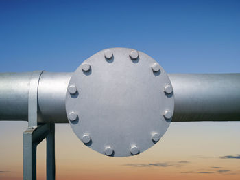 Low angle view of metal pipe against sky during sunset