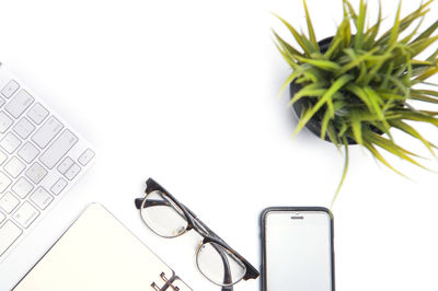 High angle view of mobile phone with computer keyboard and book over white background