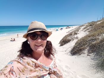 Portrait of mature woman on beach against clear sky