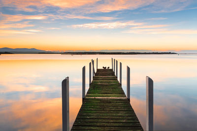 Pier over lake against sky during sunset