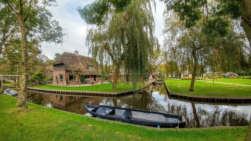 Built structure by lake and building against trees