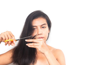 Portrait of young woman holding camera over white background