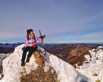 Woman sitting on rock against mountains