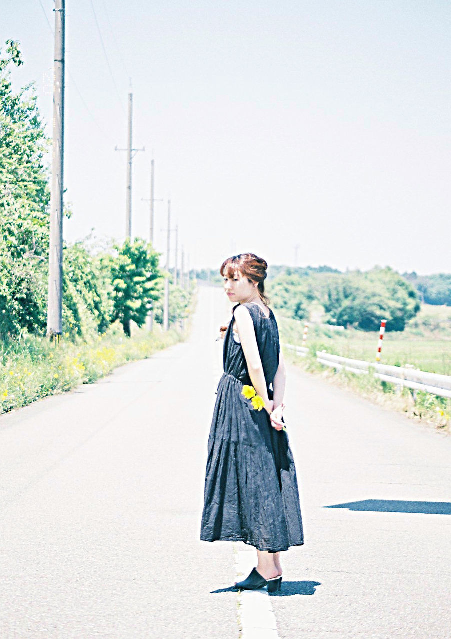 WOMAN STANDING ON ROAD AGAINST SKY