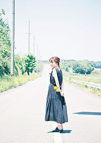 Young woman standing on road against clear sky