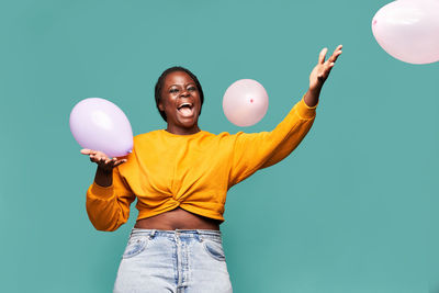 Young man with balloon standing against blue background