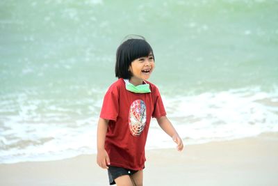 Girl laughing while standing against sea