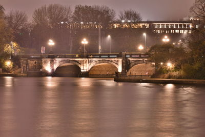 Arch bridge over river at night